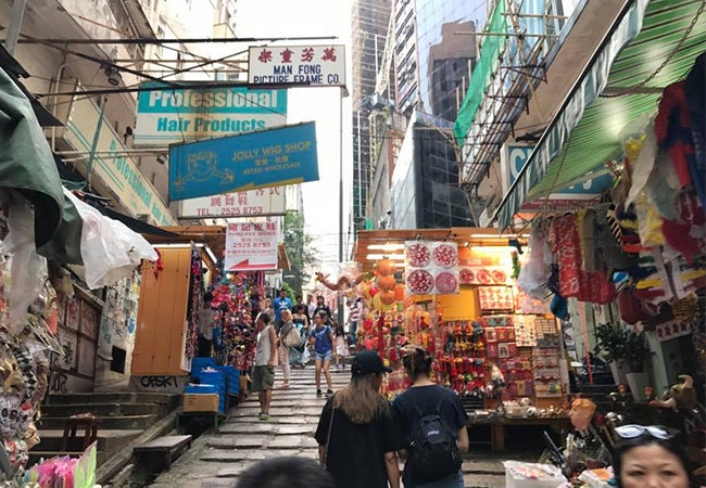 Pedestrians make their way through busy shops and stalls that line a narrow Hong Kong street. 