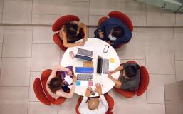 Students gathered around table with laptops