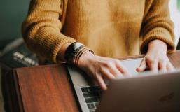 MiM - Online Convenience Person in a yellow sweater using a laptop.