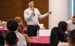 MiM Core Business Essentials Student speaking in a conference room in front of a class.