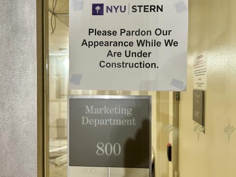 A "Please Pardon Our Appearance" sign above a sign for the NYU Stern Marketing Department