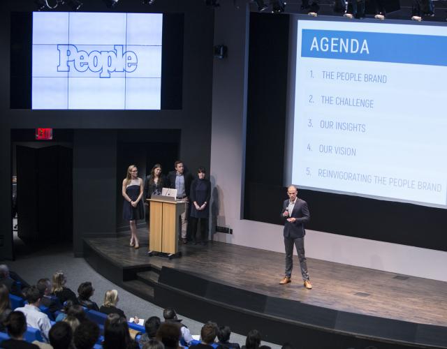 Four students presenting on a stage