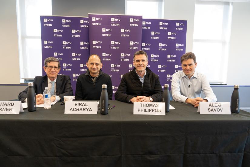 professors richard berner, viral acharya, thomas philippon, and alexi savov sitting at a table together, smiling while facing the camera