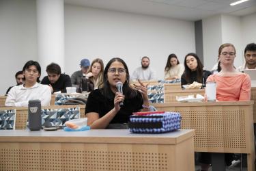 A student holds a microphone and asks a question to Liza Landsman