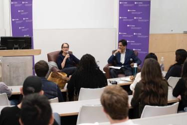 Liza Landsman and Arun Sundararajan sit in front of the audience of students