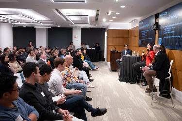 A room of attendees listen to panelists speak